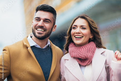 Portrait of happy couple hugging outdoors during sunny winter day