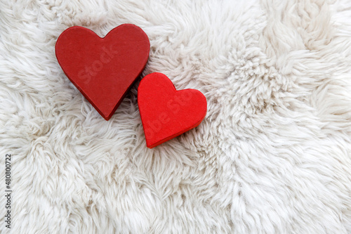 There are two paper hearts on white faux fur. Space for text. Copy space