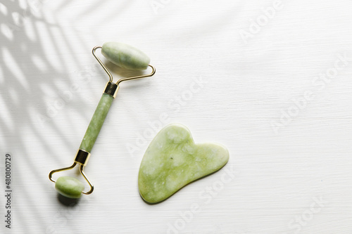 Massage set "Guasha" jade green, roller and scraper on the white background