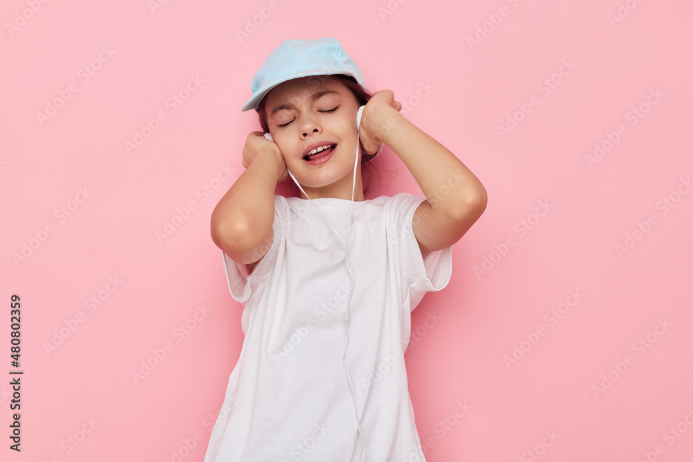 little girl headphones in a white t-shirt and a cap pink background little girl headphones in a white t-shirt and a cap pink background