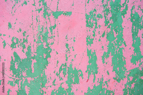 Rough, old, pink and green cement wall with many scratches in the Caribbean.