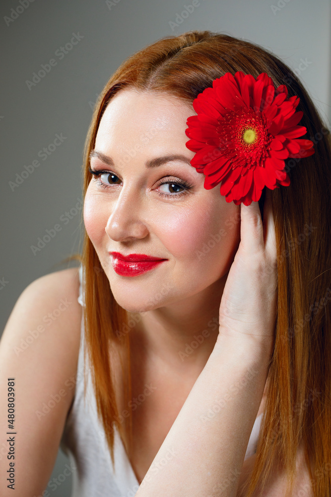 Naklejka premium Portrait of adult 40 woman with red flower and red lipstick.