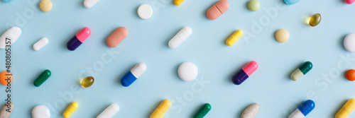 Banner made Creative layout of colorful pills and capsules on blue background. Minimal medical concept. Pharmaceutical, Covid-19 or Coronavirus. Flat lay, top view