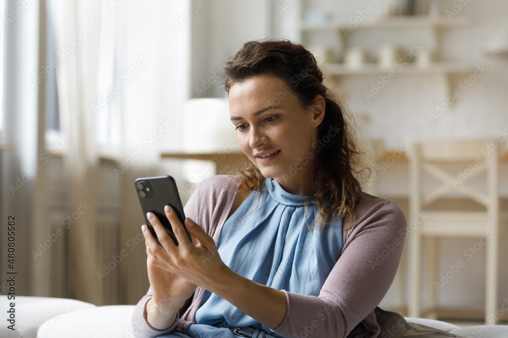 Beautiful smiling millennial woman using cellphone software application, enjoying web surfing information, posting blogging in social network, communicating online or playing games, tech addiction. Beautiful smiling millennial woman using cellphone software application, enjoying web surfing information, posting blogging in social network, communicating online or playing games, tech addiction.