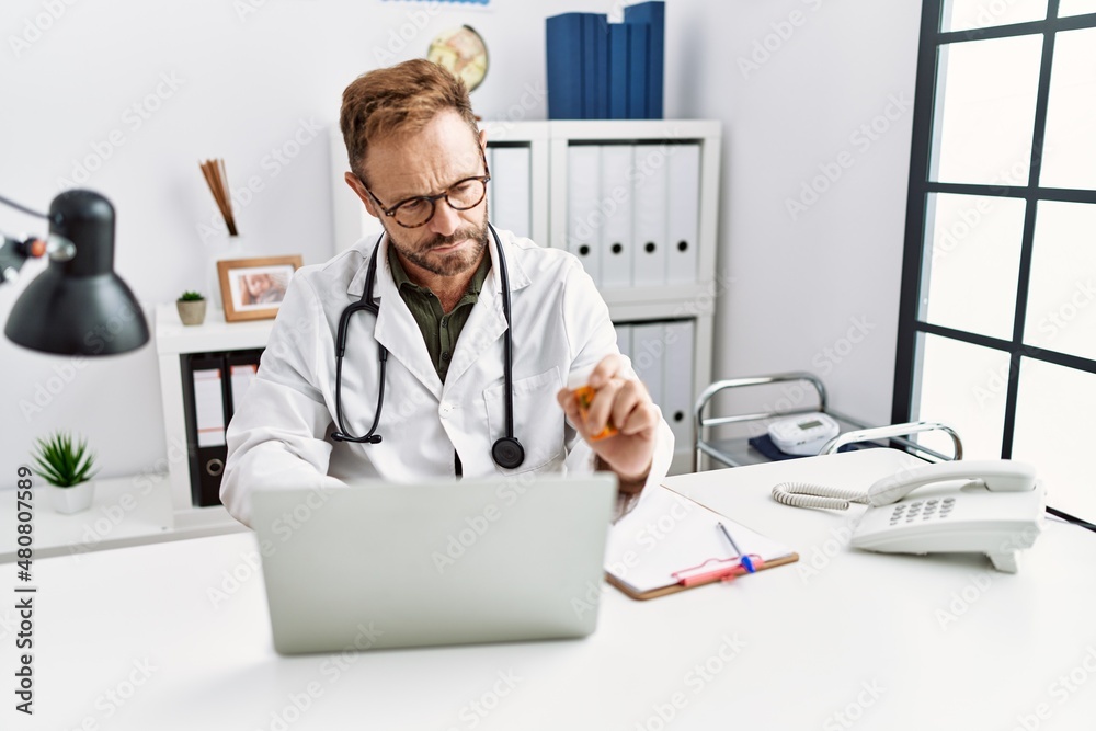 Middle age hispanic man wearing doctor uniform having video call at clinic Middle age hispanic man wearing doctor uniform having video call at clinic