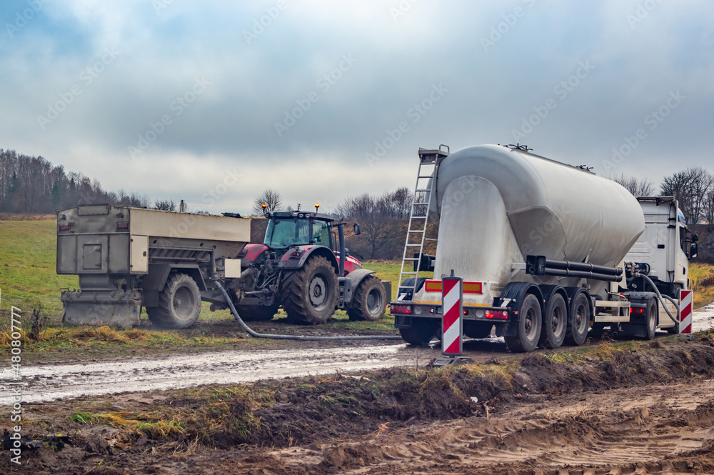 Fototapeta premium Binding agent spreader in trailer and cement tank truck on site
