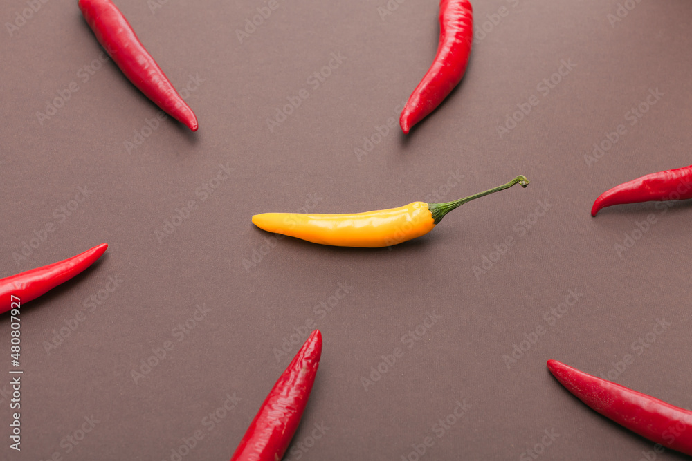 red and yellow chili peppers isolated on brown background
