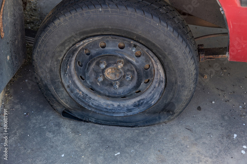 Destroyed blown out tire with exploded, shredded and damaged tire on a modern automobile. damaged truck rubber after tire explosion at high speed. Damaged flat tires: old car. © kanpisut