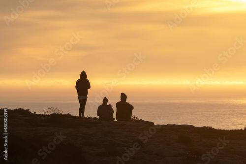 Family enjoying sunset on a cliff