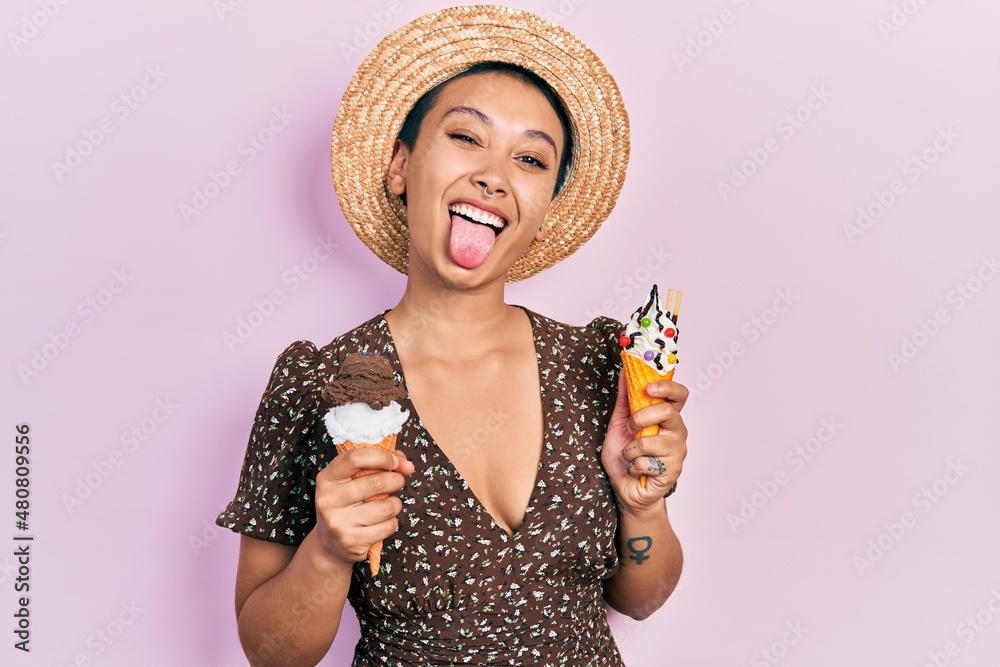 Φωτογραφία Beautiful hispanic woman with short hair eating ice cream cones sticking tongue out happy with funny expression