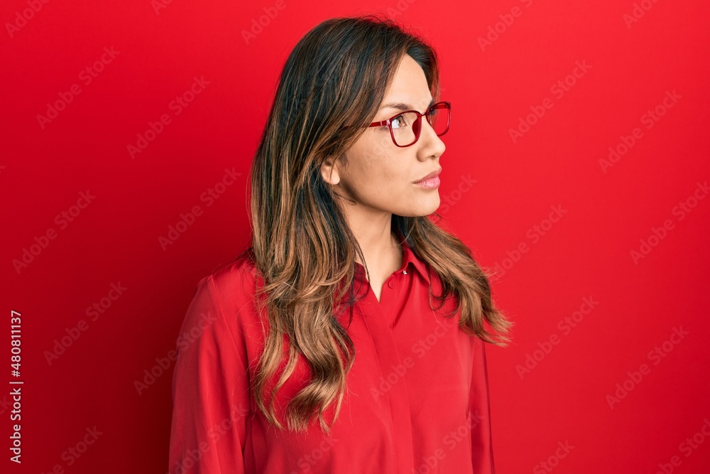 Young latin woman wearing casual clothes and glasses looking to side, relax profile pose with natural face with confident smile.