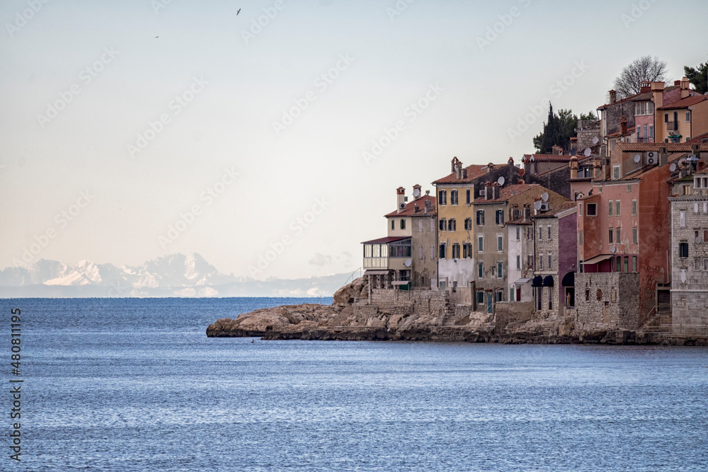 Beautiful, dense built houses of the adriatic town of Rovinj, with recognizable colorful facades against the barely visible italian alps across the sea