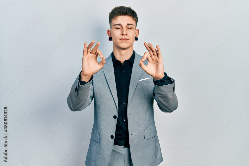 Young caucasian boy with ears dilation wearing business jacket relaxed and smiling with eyes closed doing meditation gesture with fingers. yoga concept. Young caucasian boy with ears dilation wearing business jacket relaxed and smiling with eyes closed doing meditation gesture with fingers. yoga concept.