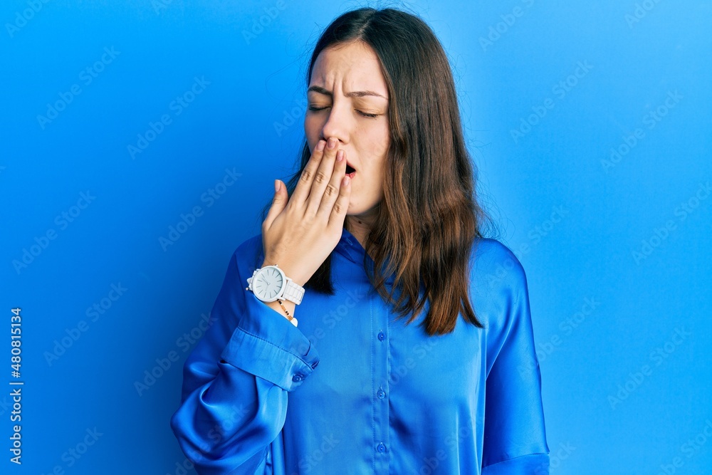 Young brunette woman wearing casual blue shirt bored yawning tired covering mouth with hand. restless and sleepiness. Young brunette woman wearing casual blue shirt bored yawning tired covering mouth with hand. restless and sleepiness.
