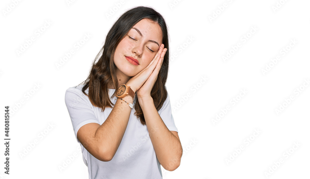 Young beautiful woman wearing casual white t shirt sleeping tired dreaming and posing with hands together while smiling with closed eyes. Young beautiful woman wearing casual white t shirt sleeping tired dreaming and posing with hands together while smiling with closed eyes.