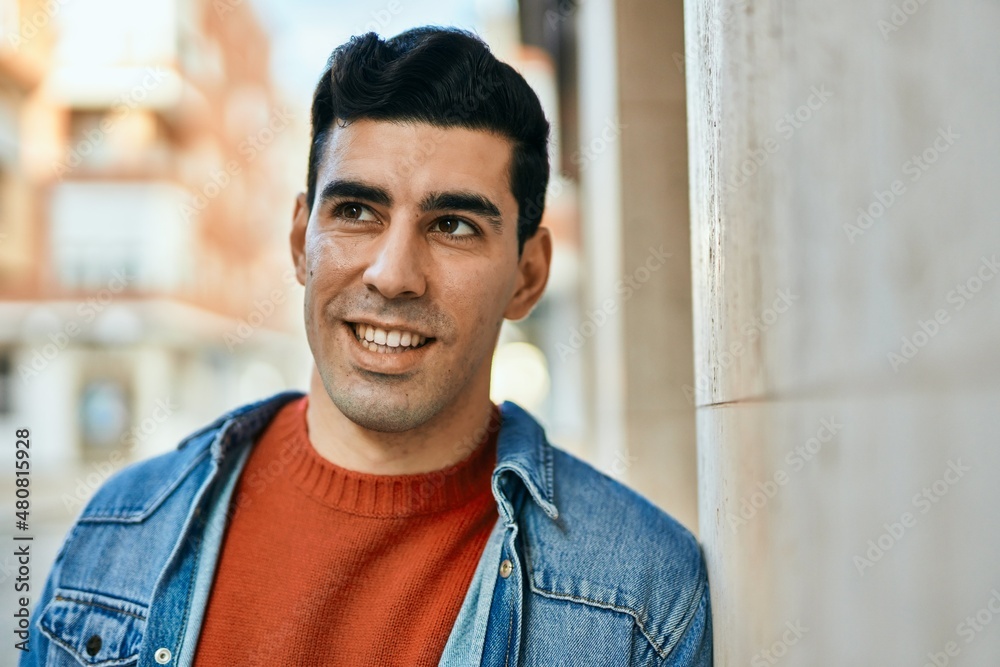 Young hispanic man smiling happy standing at the city.