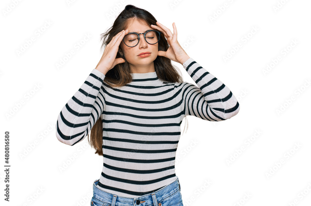 Young beautiful teen girl wearing casual clothes and glasses with hand on head for pain in head because stress. suffering migraine. Young beautiful teen girl wearing casual clothes and glasses with hand on head for pain in head because stress. suffering migraine.