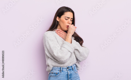 pretty young woman feeling ill with a sore throat and flu symptoms, coughing with mouth covered photo