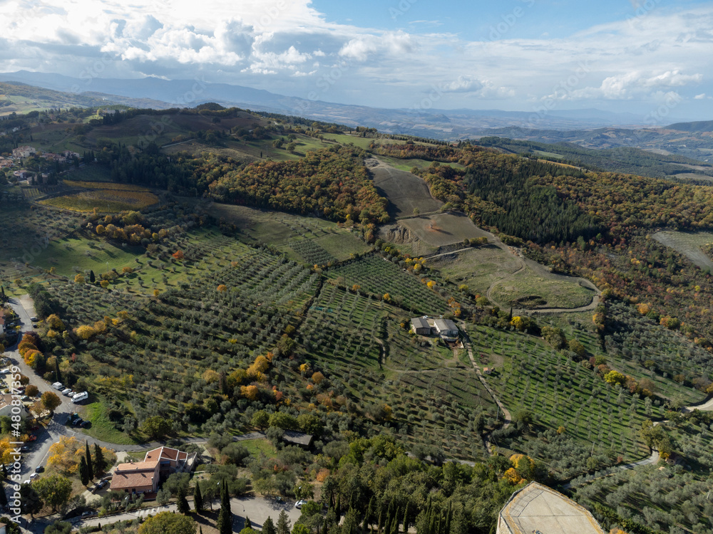 Fototapeta premium Aerial view on hills of Val d'Orcia near Castiglione d'Orcia, Tuscany, Italy. Tuscan landscape with cypress trees, vineyards, forests and ploughed fields in autumn.