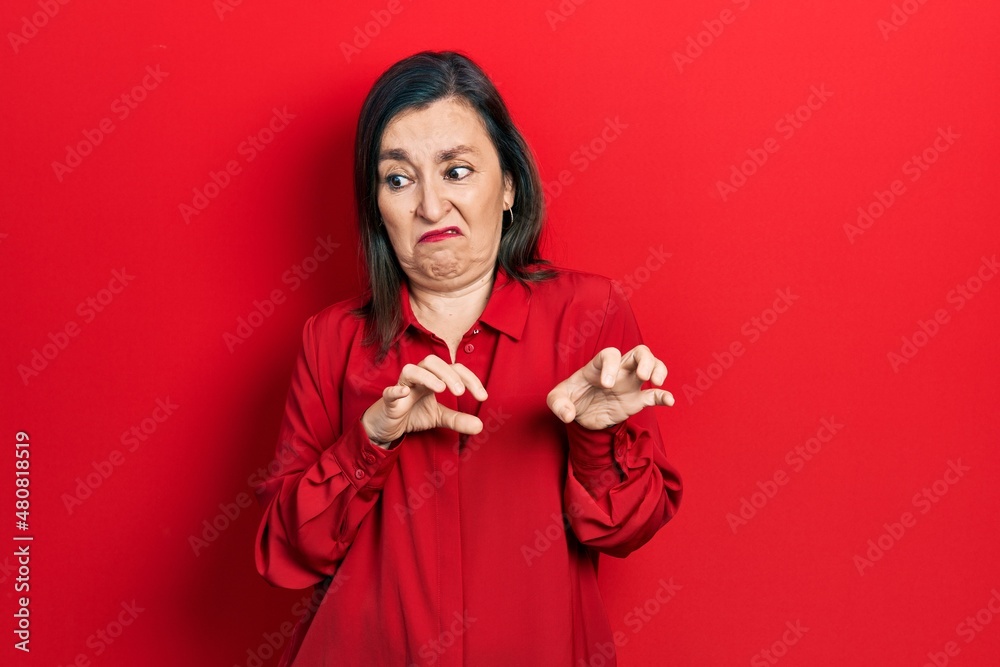 Middle age hispanic woman wearing casual clothes disgusted expression, displeased and fearful doing disgust face because aversion reaction. Middle age hispanic woman wearing casual clothes disgusted expression, displeased and fearful doing disgust face because aversion reaction.