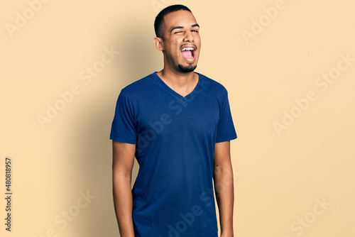 Young african american man wearing casual t shirt winking looking at the camera with sexy expression, cheerful and happy face. © Krakenimages.com