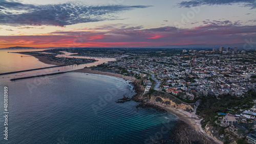 Aerial view of the ocean and a coastal California community at sunset.
