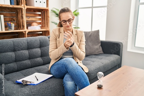 Bild auf Leinwand Young woman working at consultation office suffering pain on hands and fingers,