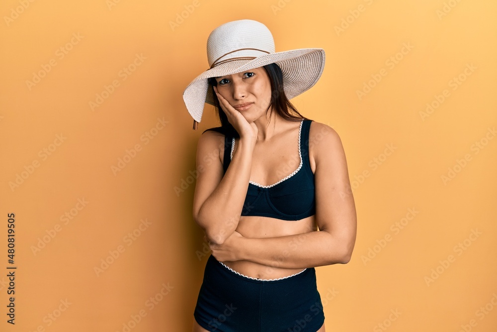 Young latin woman wearing bikini and summer hat thinking looking tired and bored with depression problems with crossed arms. Young latin woman wearing bikini and summer hat thinking looking tired and bored with depression problems with crossed arms.