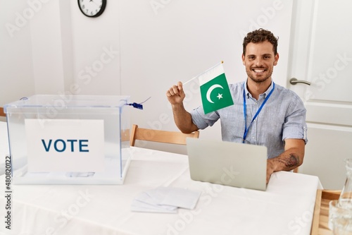 Young hispanic man smiling confident holding pakistan flag working at electoral college