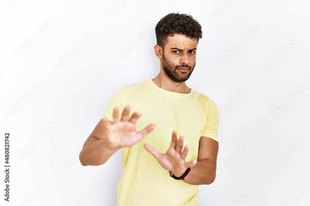 Arab young man standing over isolated background disgusted expression, displeased and fearful doing disgust face because aversion reaction. with hands raised Arab young man standing over isolated background disgusted expression, displeased and fearful doing disgust face because aversion reaction. with hands raised