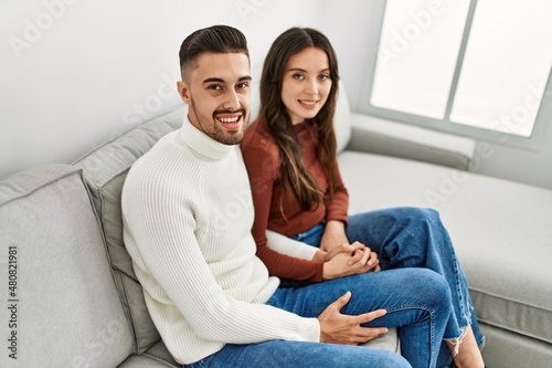 Young hispanic couple hugging and resting on the sofa and at home.