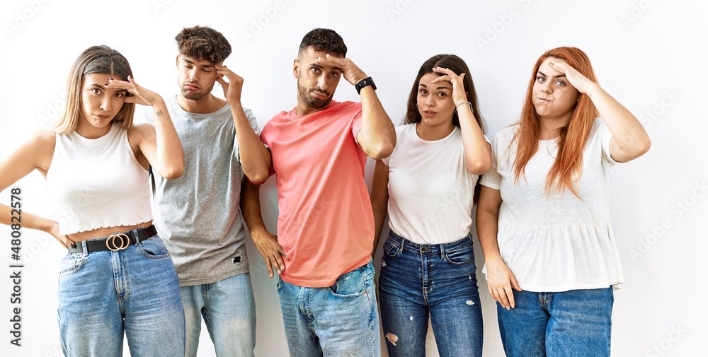 Obraz premium Group of young friends standing together over isolated background worried and stressed about a problem with hand on forehead, nervous and anxious for crisis