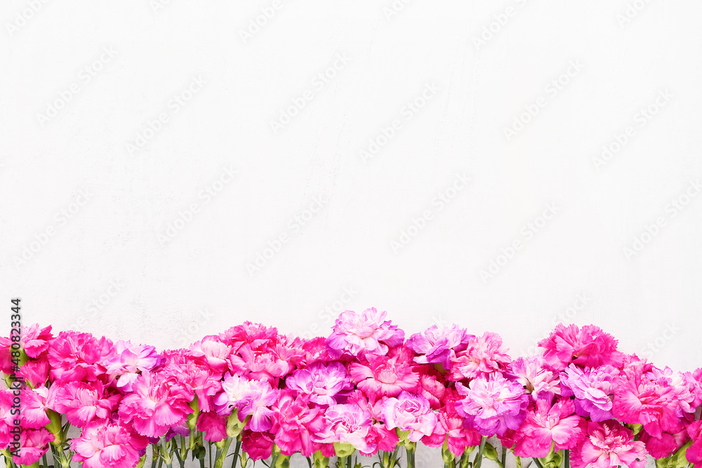 Obraz premium Pink carnation flowers border on a light background. Flat lay, copy space