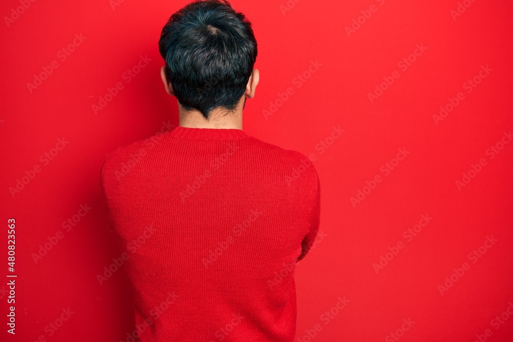 Handsome man with beard wearing casual red sweater standing backwards looking away with crossed arms Handsome man with beard wearing casual red sweater standing backwards looking away with crossed arms