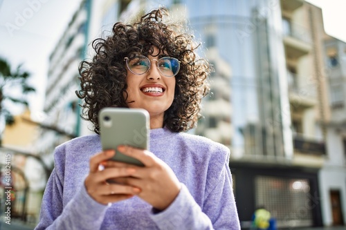 Young middle east woman smiling confident using smartphone at street