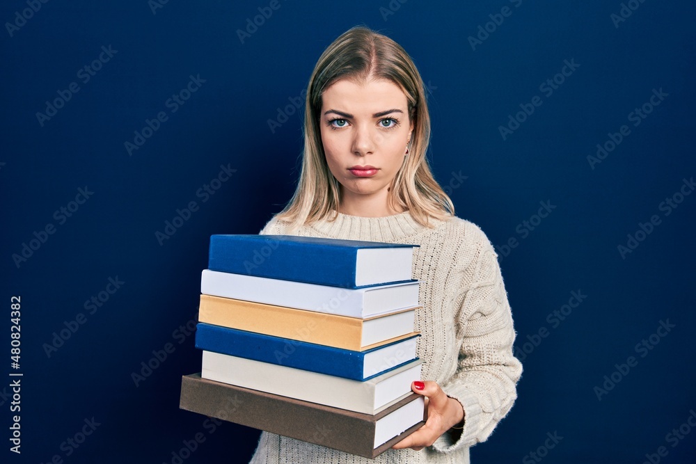 Beautiful caucasian woman holding a pile of books depressed and worry for distress, crying angry and afraid. sad expression. Beautiful caucasian woman holding a pile of books depressed and worry for distress, crying angry and afraid. sad expression.