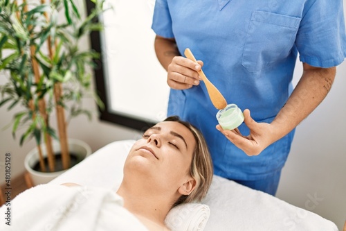 Woman couple having facial treatment using aloe vera cream at beauty center photo
