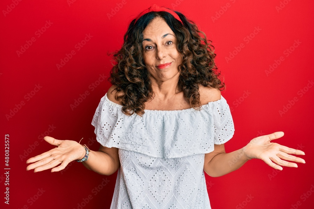 Middle age hispanic woman wearing casual clothes clueless and confused expression with arms and hands raised. doubt concept. Middle age hispanic woman wearing casual clothes clueless and confused expression with arms and hands raised. doubt concept.