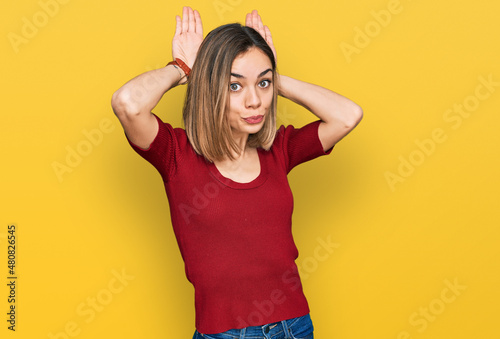 Young blonde girl wearing casual clothes doing bunny ears gesture with hands palms looking cynical and skeptical. easter rabbit concept.