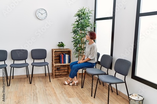 Young caucasian girl bored sitting on the chair at waiting room.