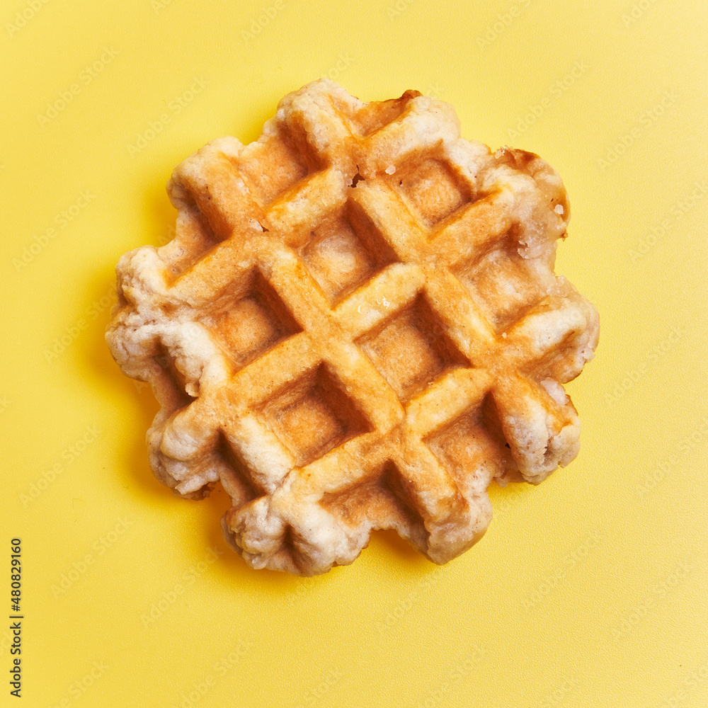 Single delicious waffle over yellow background Single delicious waffle over yellow background