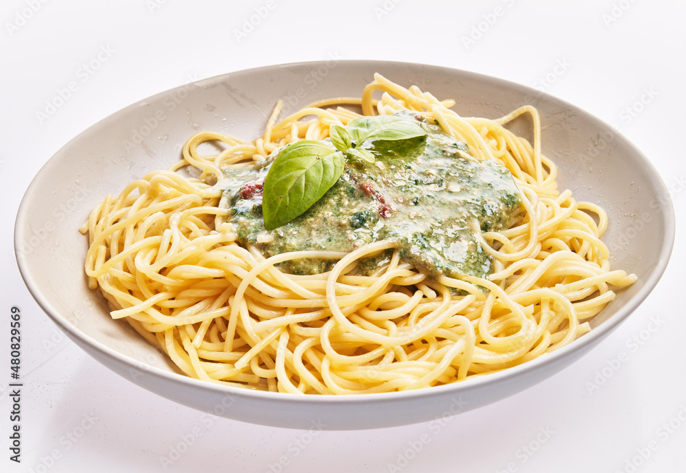 Plate of italian spaghetti pasta with pesto sauce over white isolated background Plate of italian spaghetti pasta with pesto sauce over white isolated background