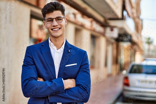 Obraz na plátně Young man smiling confident wearing suit and glasses at street