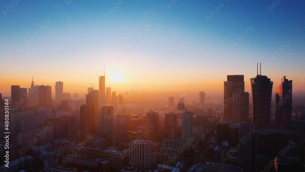 Morning flight over Warsaw. Aerial sunrise and fog oover Warsaw downtown skyline with skyscrapers, Poland. Reflections of the sun in the glass of a skyscraper Morning flight over Warsaw. Aerial sunrise and fog oover Warsaw downtown skyline with skyscrapers, Poland. Reflections of the sun in the glass of a skyscraper