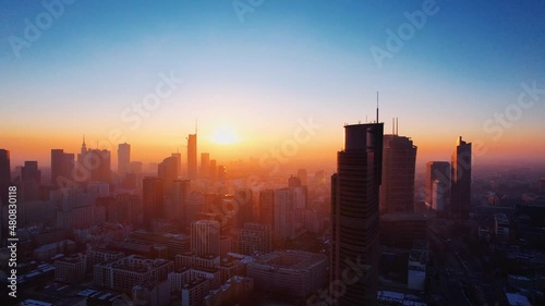 Morning flight over Warsaw. Aerial sunrise and fog oover Warsaw downtown skyline with skyscrapers, Poland. Reflections of the sun in the glass of a skyscraper photo