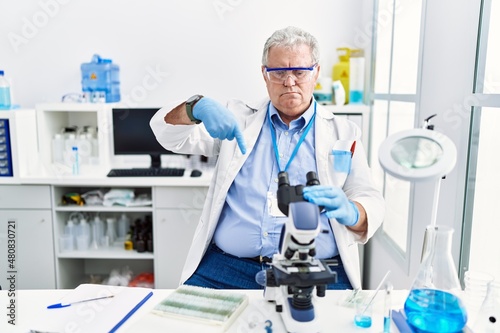 Senior caucasian man working at scientist laboratory pointing down looking sad and upset  indicating direction with fingers  unhappy and depressed.