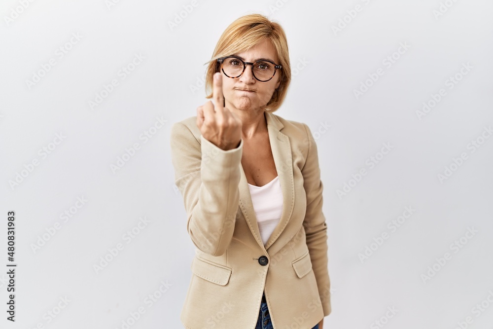 Middle age blonde business woman standing over isolated background showing middle finger, impolite and rude fuck off expression Middle age blonde business woman standing over isolated background showing middle finger, impolite and rude fuck off expression