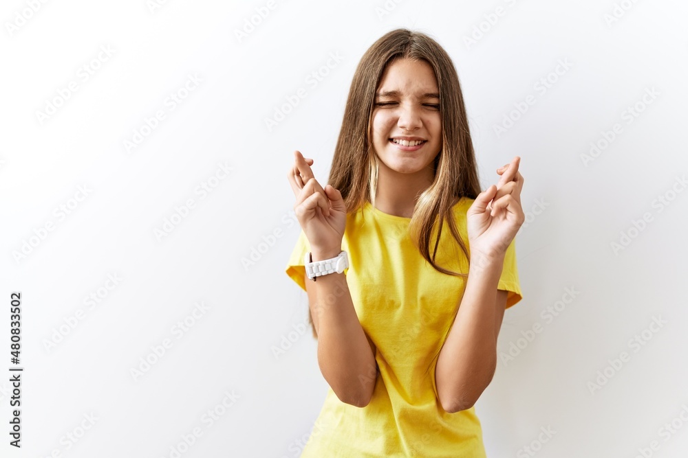 Young brunette teenager standing together over isolated background gesturing finger crossed smiling with hope and eyes closed. luck and superstitious concept. Young brunette teenager standing together over isolated background gesturing finger crossed smiling with hope and eyes closed. luck and superstitious concept.