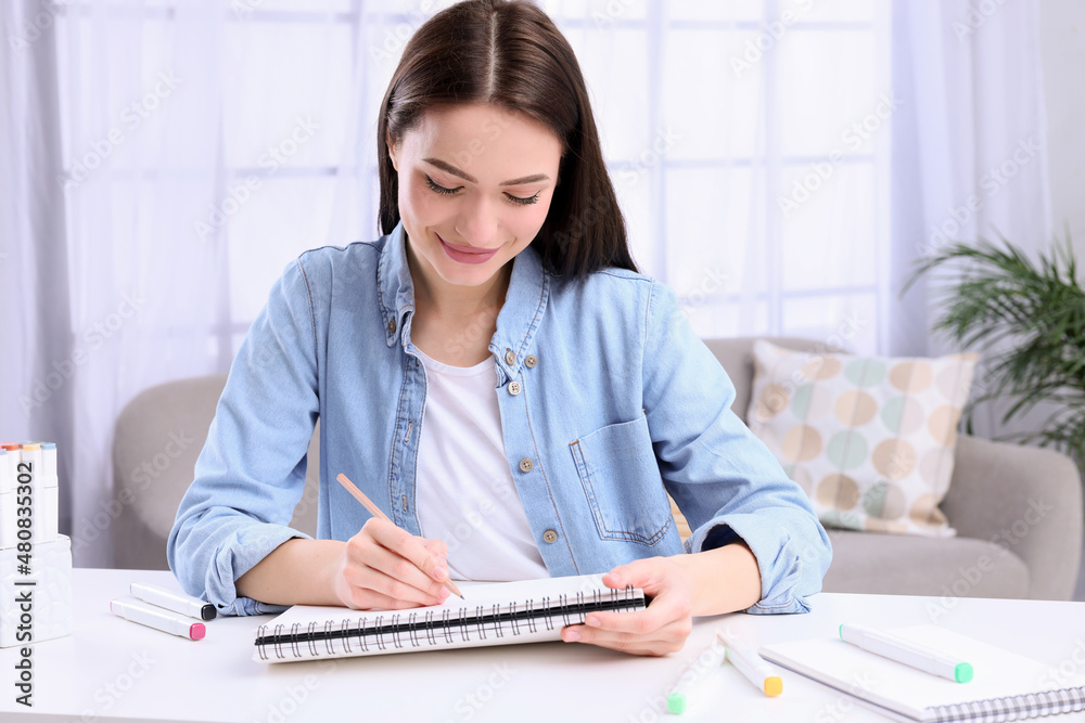 Young woman drawing in sketchbook at home Young woman drawing in sketchbook at home