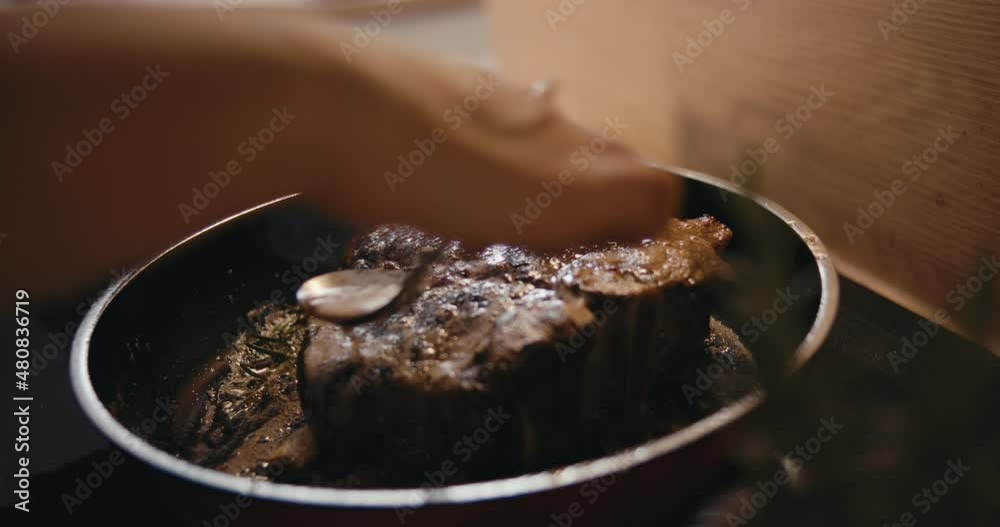 Female cook saucing beef steak kitchen pan stoveslow motion close up Female cook saucing beef steak kitchen pan stoveslow motion close up